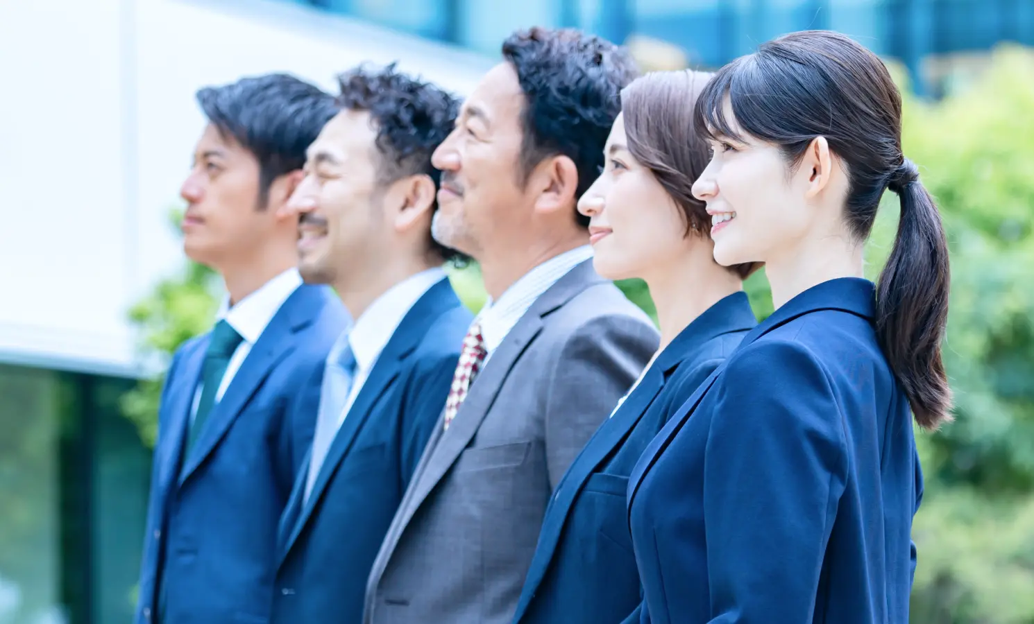 5名の社員が並んで上を見ている様子を横から写した写真