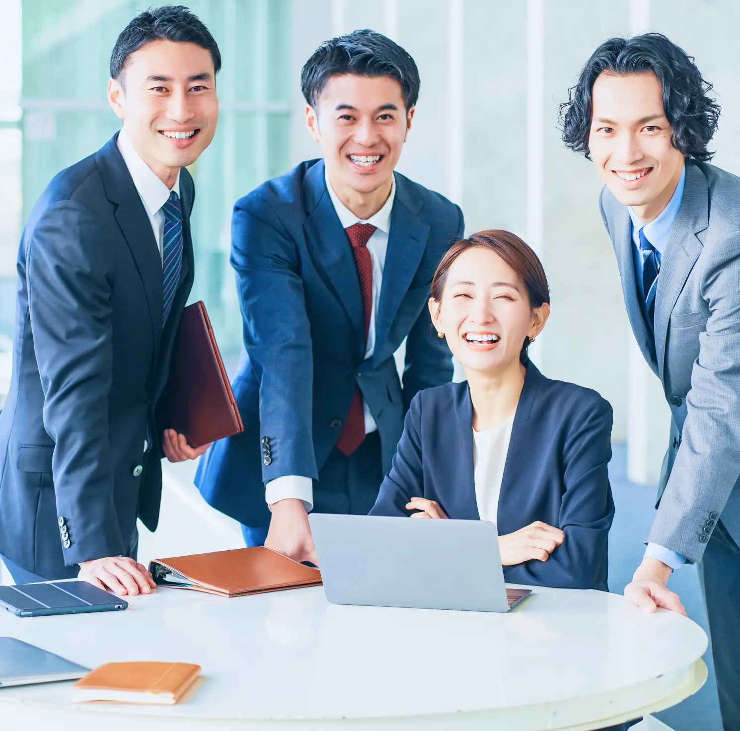 4人の社員が笑顔で正面を見ている様子