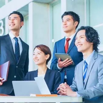 パソコンを持った4人の社員が笑顔で上を見ている様子